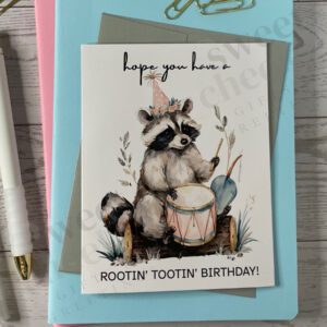 Greeting card featuring Rootin' Tootin' Birthday Country raccoon playing blue grass drum in the woods