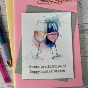Greeting card featuring two wine glasses anniversary card with message "cheers to a lifetime of happy anniversaries"