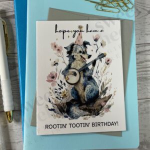 Greeting card featuring Rootin' Tootin' Birthday Country Dog playing blue grass banjo in the woods