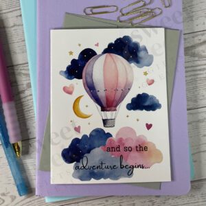 New baby greeting card with message "and so the adventure begins" featuring hot air balloon stars hearts clouds and the moon