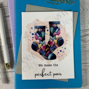 Geeting card that features colorful socks covered in hearts and says "we make the perfect pair"