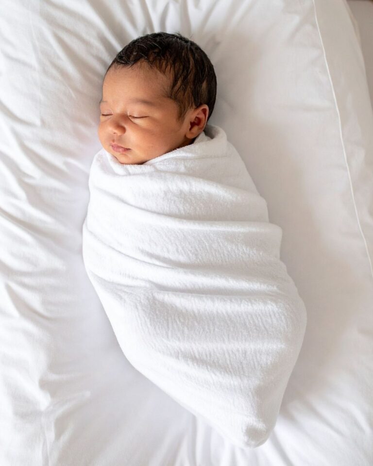 newborn baby swaddled in muslin nursing blanket sleeping